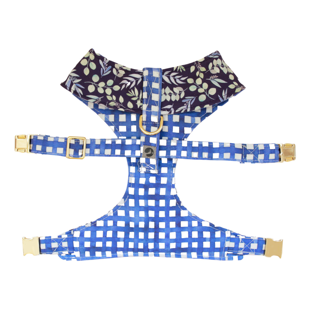 Top view of reversible dog harness with gold hardware in indigo background with mult-color foliage